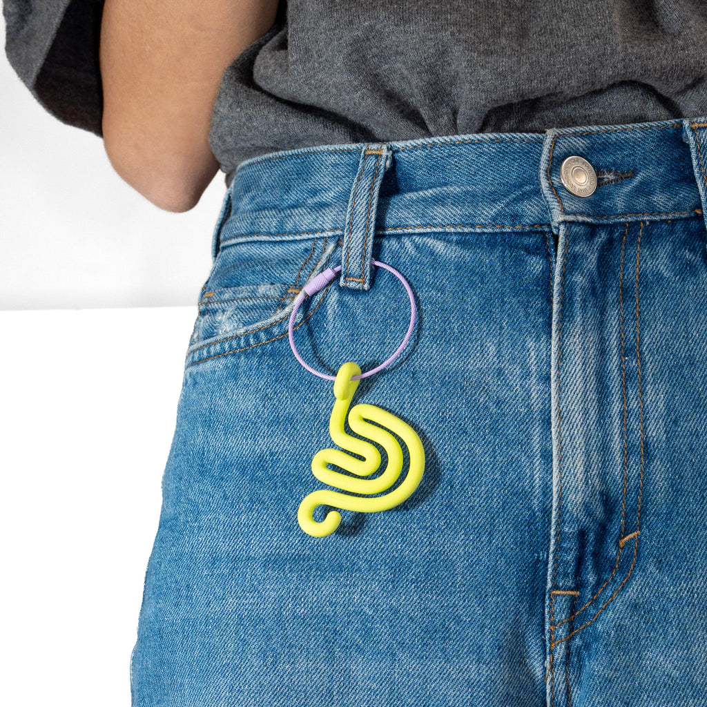 Person wearing a denim pants with a lime green snail-shaped keychain.