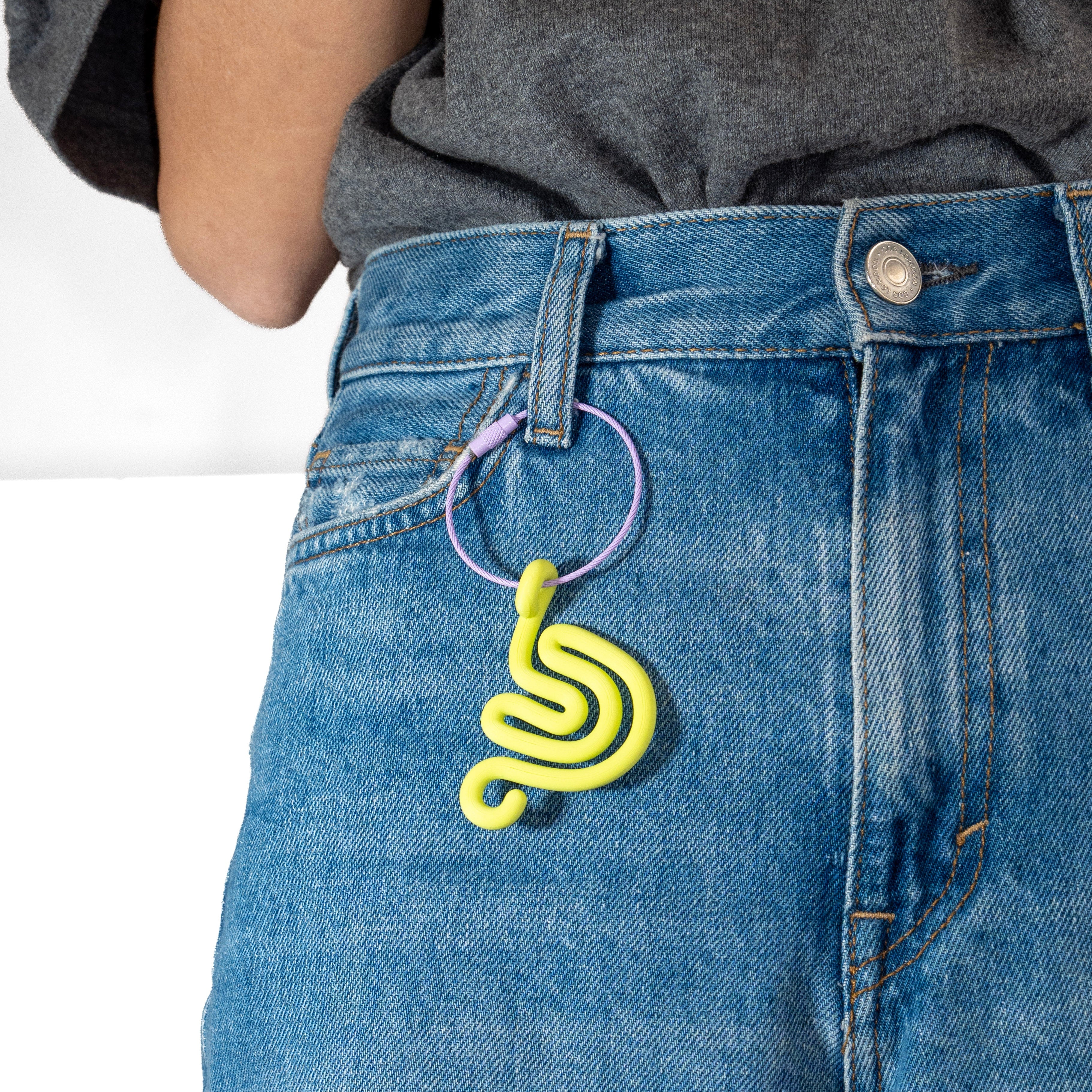 Person wearing a denim pants with a lime green snail-shaped keychain.