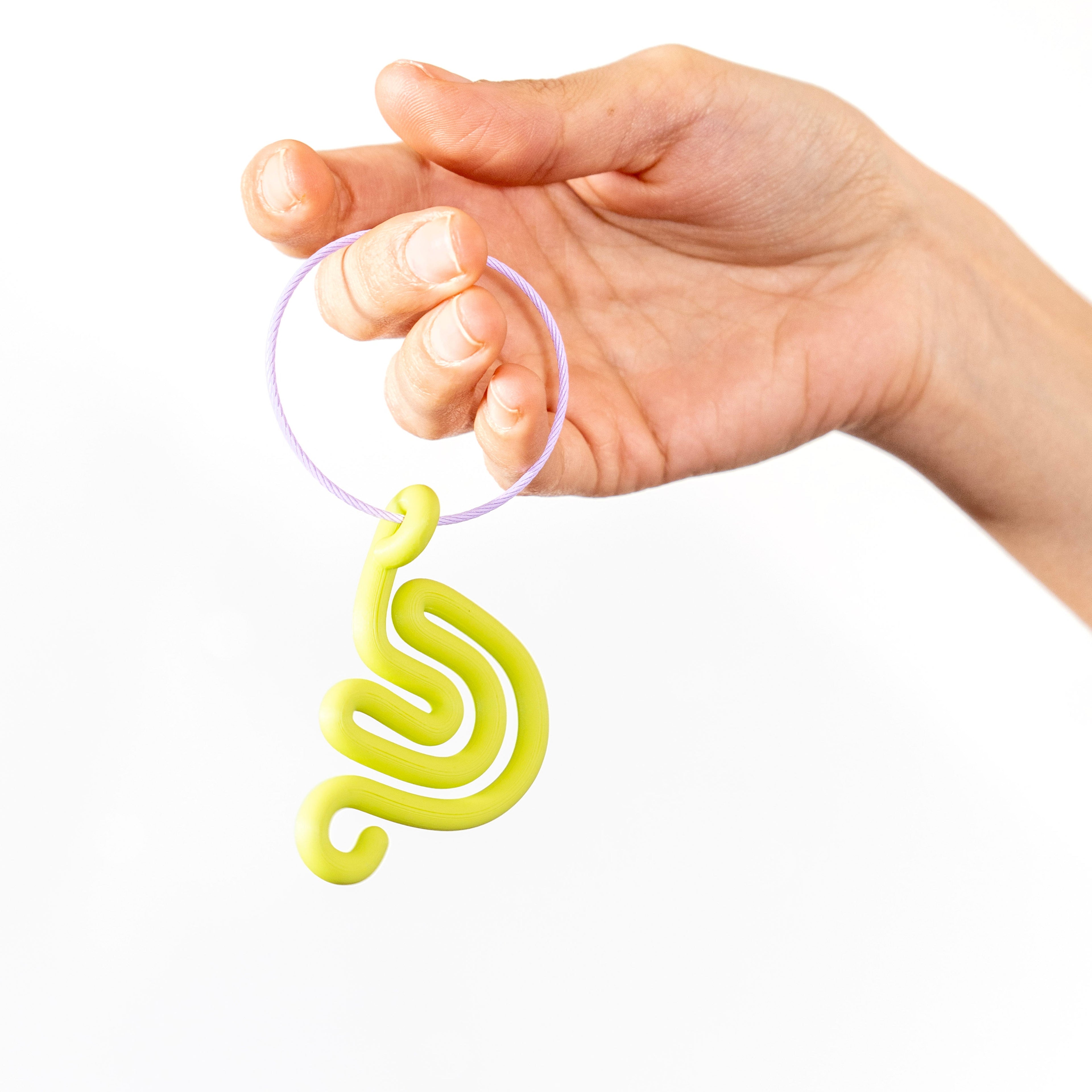 Hand holding a lime green snail shaped charm with a white background