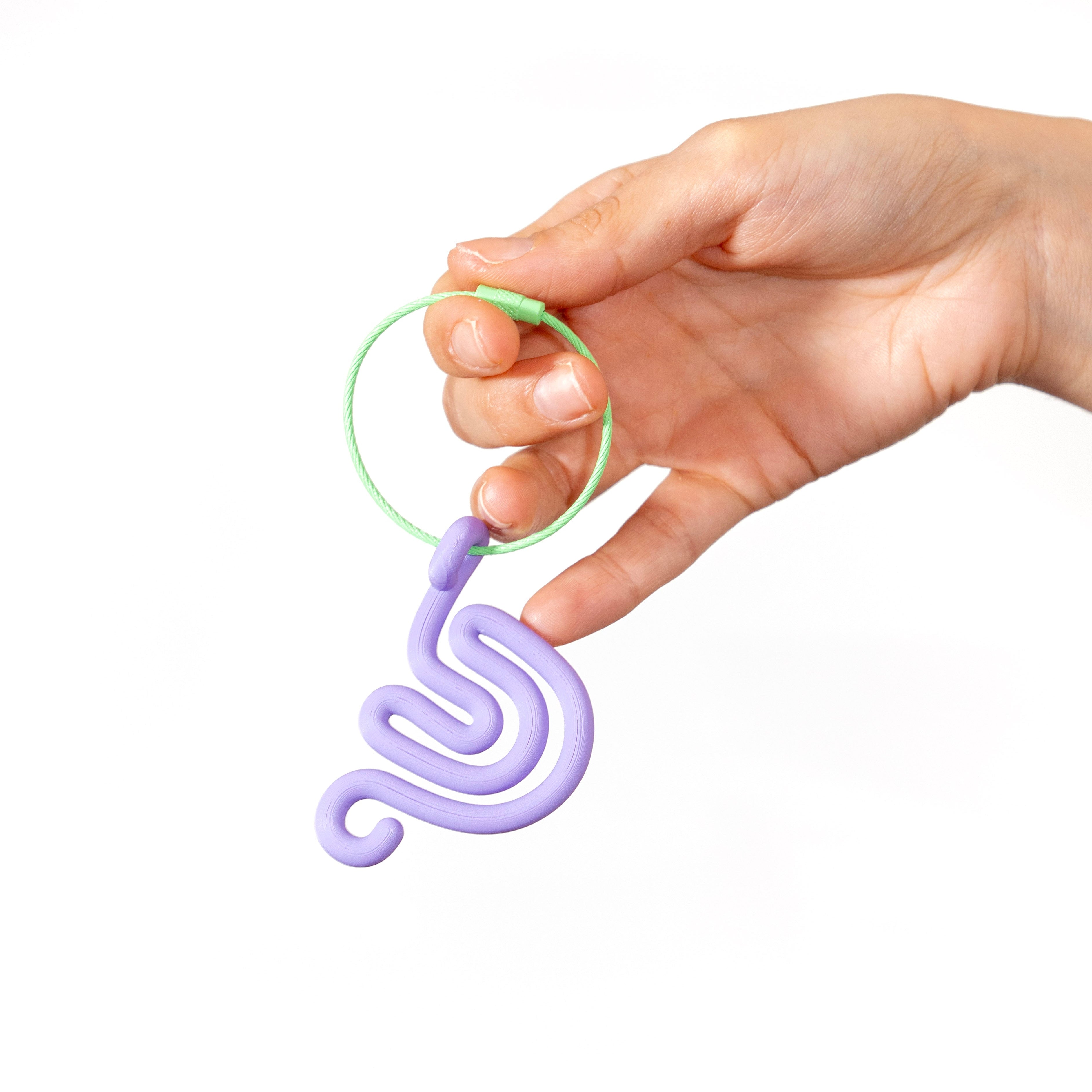 Hand holding a purple snail shaped keychain against a white background