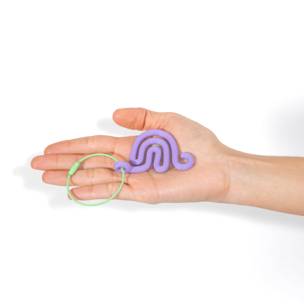 Hand holding a purple snail shaped keychain against a white background