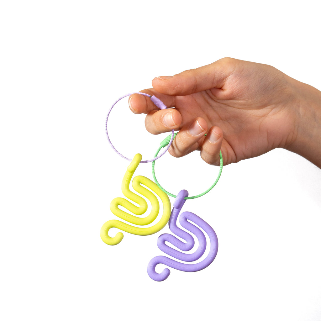 Hand holding a colorful spiral snail shaped keychain against a white background