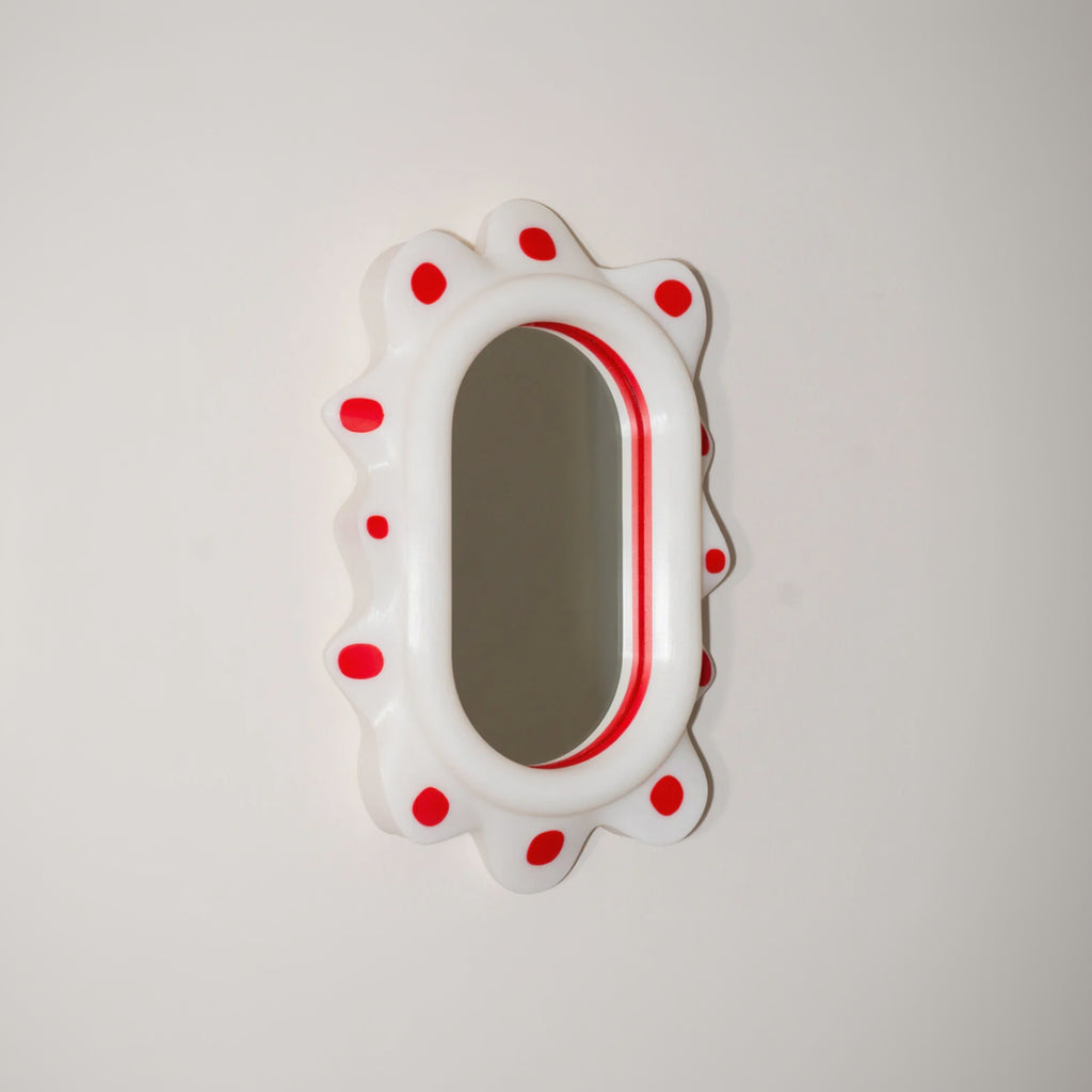 Decorative mirror with red polka dots on a light gray background