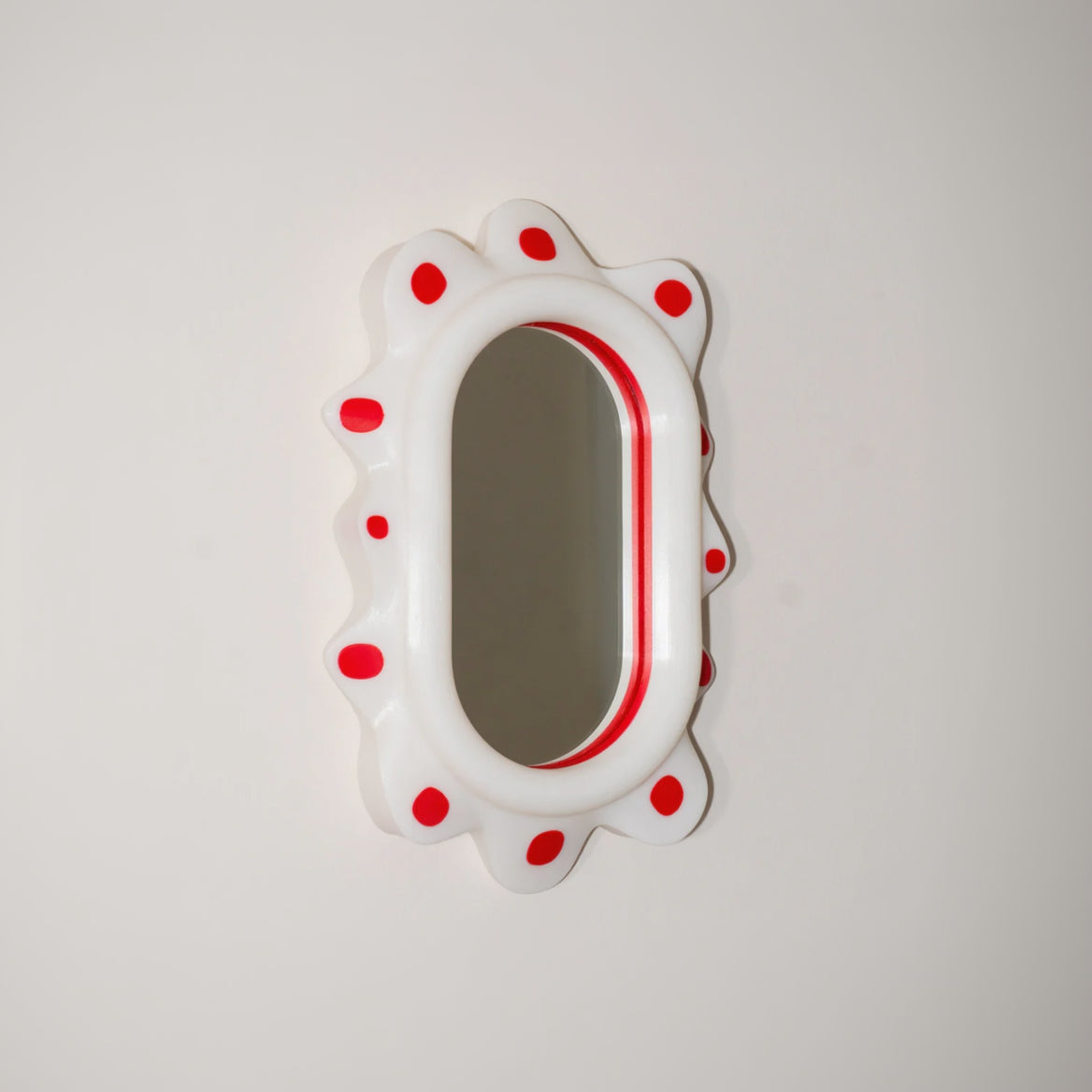 Decorative mirror with red polka dots on a light gray background