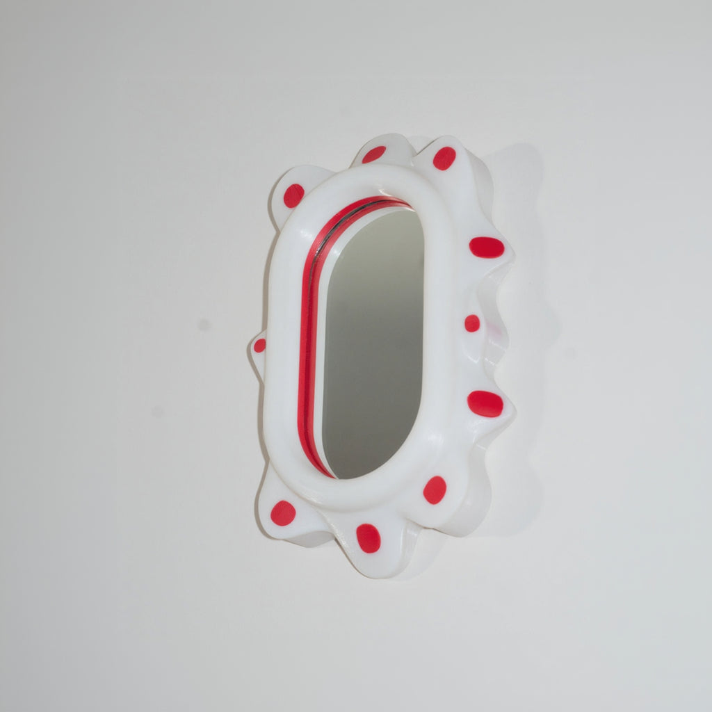 Small round mirror with red polka dot border on a white background