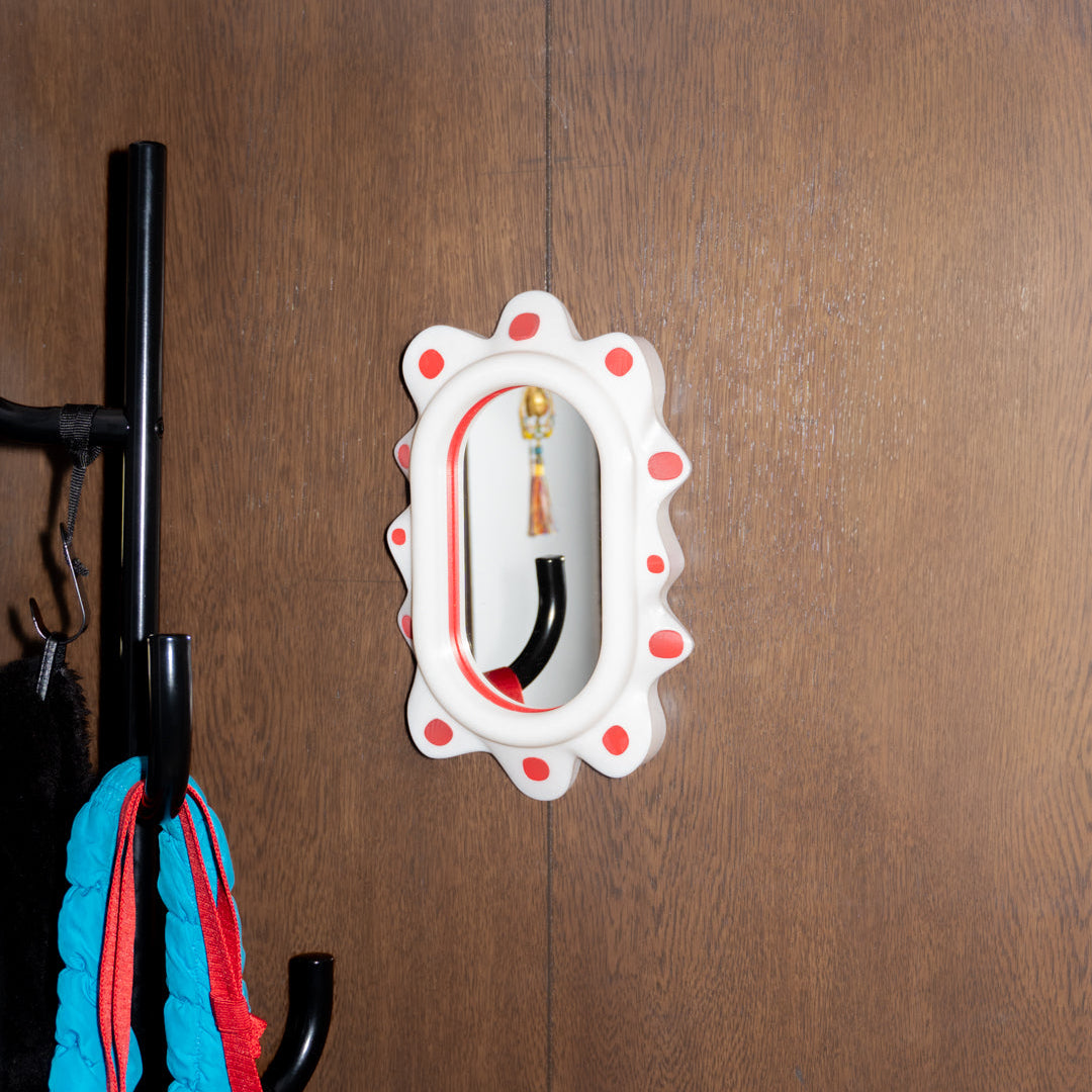 Decorative mirror with a polka dot design on a wooden wall