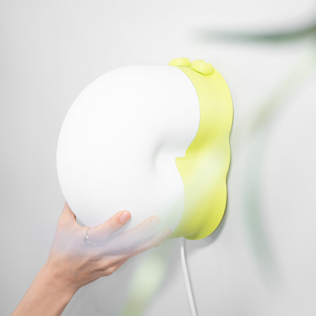 White and yellow snail lamp held by a hand against a blurred background