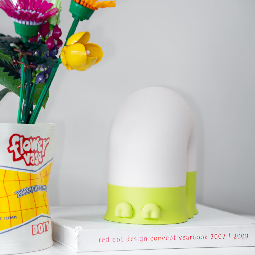 Flower vase with colorful flowers and a green and white lamp on a shelf.