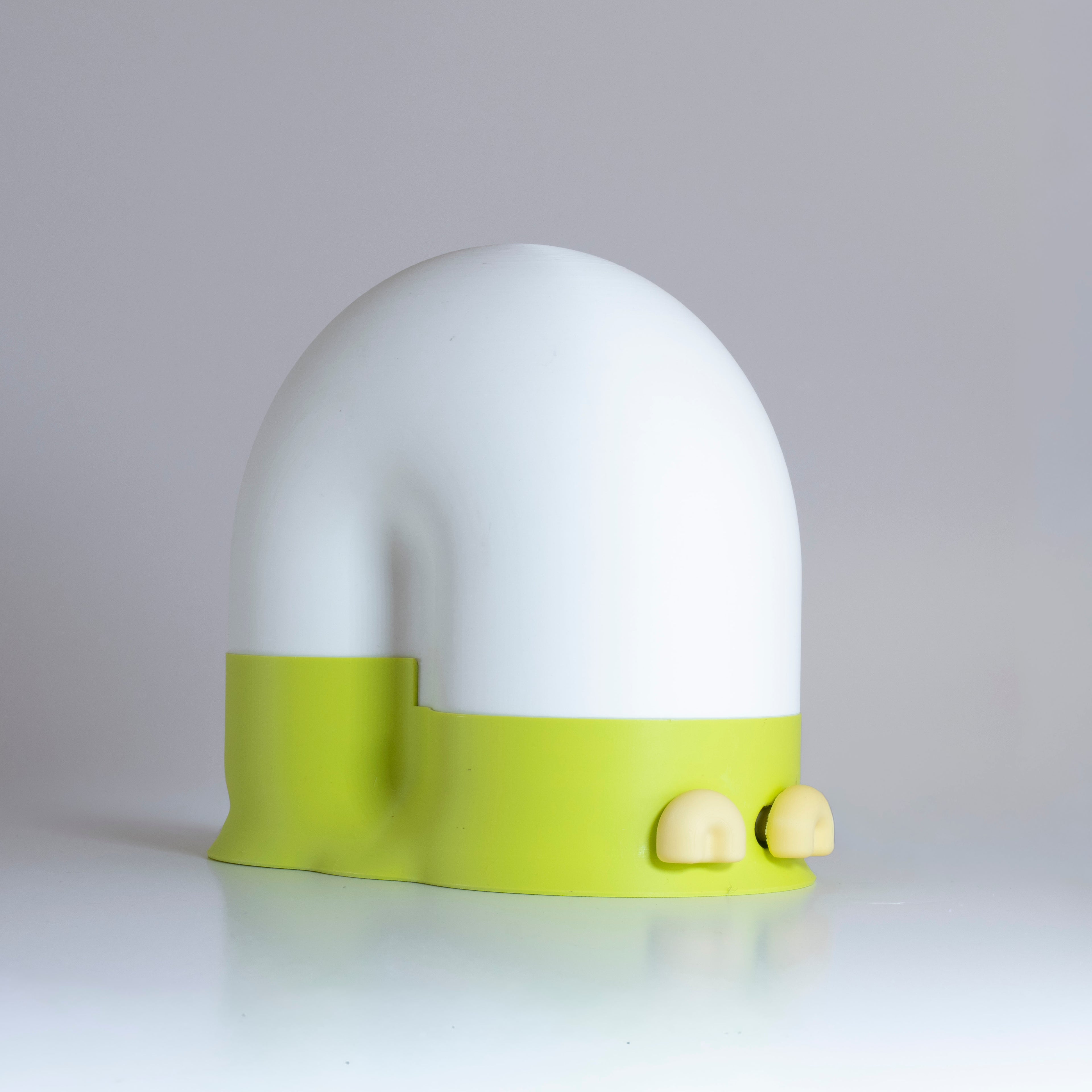 White snail-shaped lamp with a lime green base and  pastel banana eyes on a light gray background