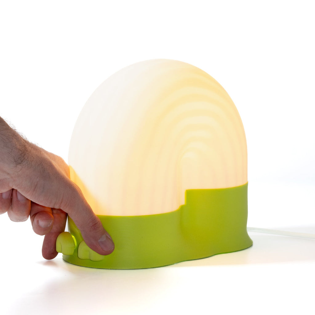 Hand holding a green and white lamp on a white background