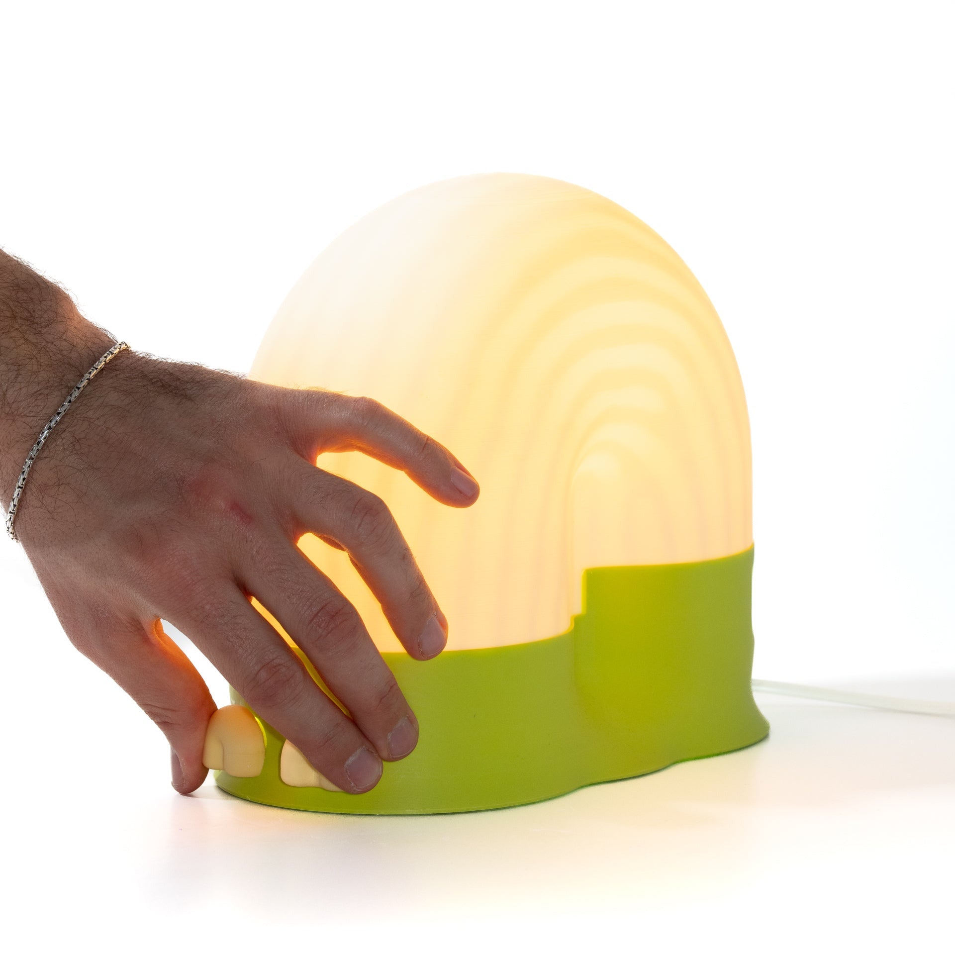 Hand interacting with a glowing green and white lamp on a white background