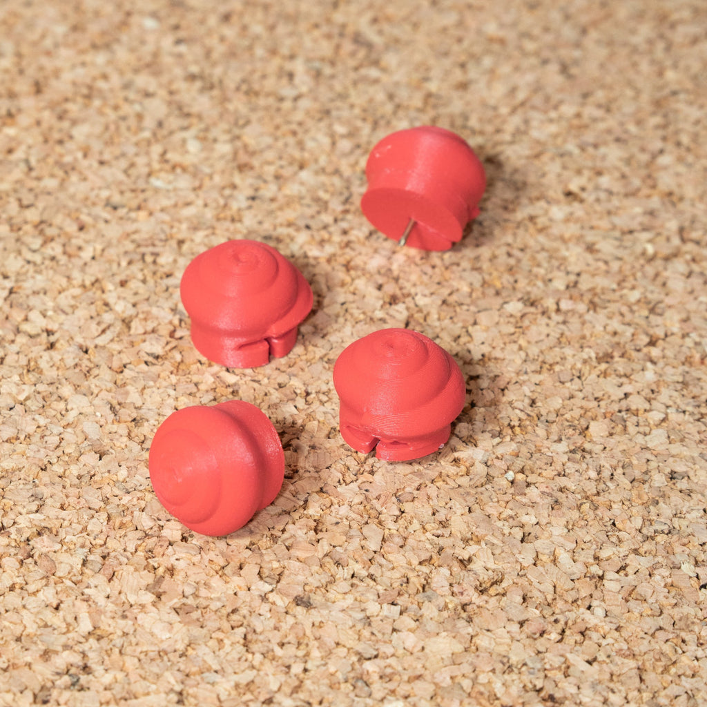 Four red pins on top of a cork surface