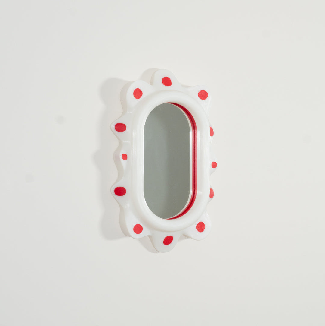 Decorative mirror with red polka dot frame on a white background